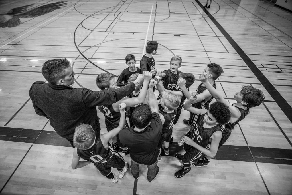 A coach surrounded with a group of players illustrating how to scale a sports club